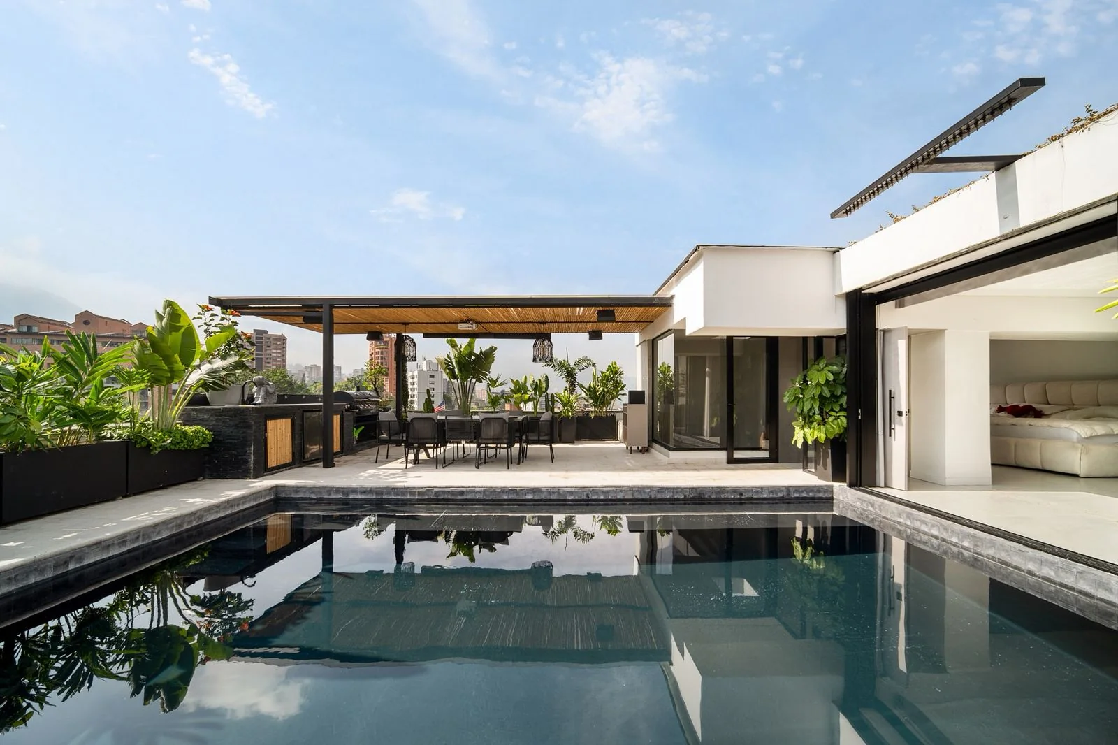 Piscina de la terraza con comedor exterior y arquitectura de líneas blancas